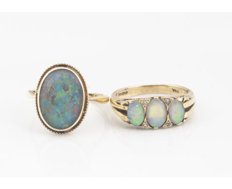 A 9ct gold three stone precious opal dress ring, the three oval cabochons alternatley set with eight cut cubic zirconias toge