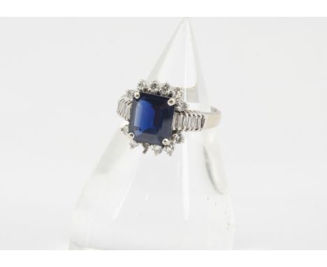 A sapphire and diamond dress ring, the step cut in four claw setting surrounded by brilliant cut and baguette cut diamonds on