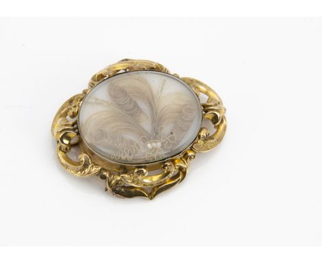 A 19th Century mourning brooch, the yellow metal surround centred with a plaited hair and gilt centre within a scoll mount, t