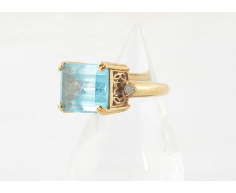 A contemporary topaz dress ring, the step cut blue topaz in a four claw setting with pierced gallery and topaz set shoulders,