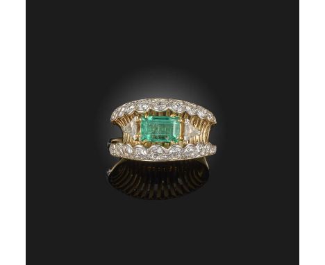 An emerald and diamond dress ring, the step-cut emerald flanked with triangular-shaped diamonds within scallop-edged borders 