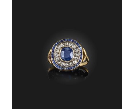 A sapphire and diamond ring, of target design, centring on a cushion-shaped sapphire, within concentric borders of rose-cut d