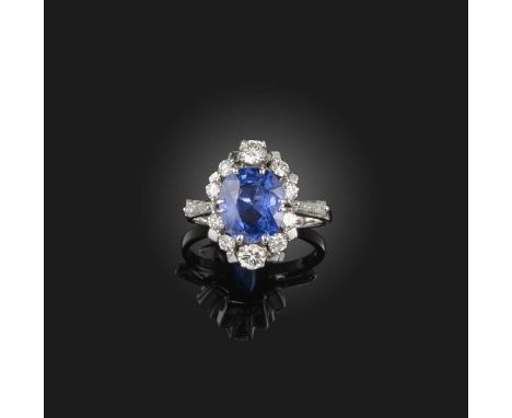 A sapphire and diamond ring, set with a cushion-shaped sapphire weighing 3.02 carats, within a border of brilliant-cut diamon