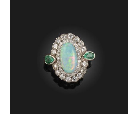 An opal, emerald and diamond ring, claw-set with an oval cabochon opal, within a double border of circular-cut diamonds, the 