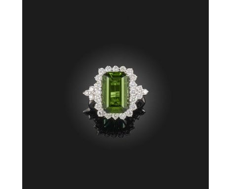 A tourmaline and diamond ring, claw-set with a step-cut green tourmaline weighing approximately 7.00 carats, to a surround of