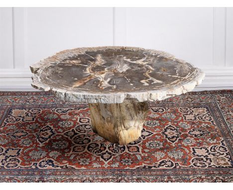 A PART POLISHED PETRIFIED WOOD CENTRE TABLE The top sliced in cross section, the trunk base with textured edges 50cm high, th
