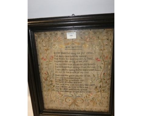 A Victorian sampler by Elizabeth Smith (undated) depicting a hymn surrounded by silk floral decoration and a bow, glazed and 