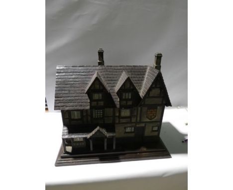 An English late Victorian carved and painted model of a Tudor house, with tiled roof, black and white half timber facade and 