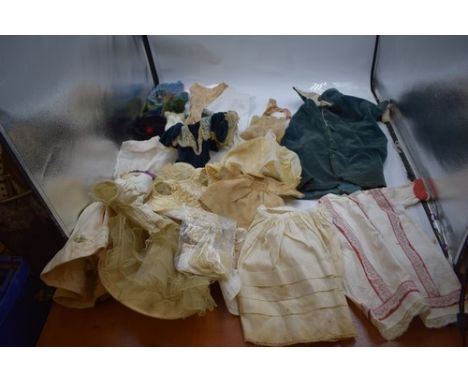 A collection of assorted doll outfits including undergarments, a white cotton dress with red trim and lace edging etc.