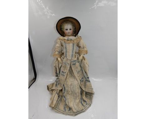 A pressed bisque 1880's fashion doll with swivel head, fixed blue glass eyes, brown feathered brows, closed mouth, pierced ea