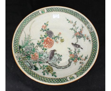 A 20th century Chinese crackle-glaze pottery charger decorated with birds amidst trees and sprouting flowers, character marks
