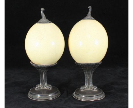 A pair of George IV silver-mounted ostrich eggs, each mounted with an ostrich 'head' finial and each supported on a pair of f
