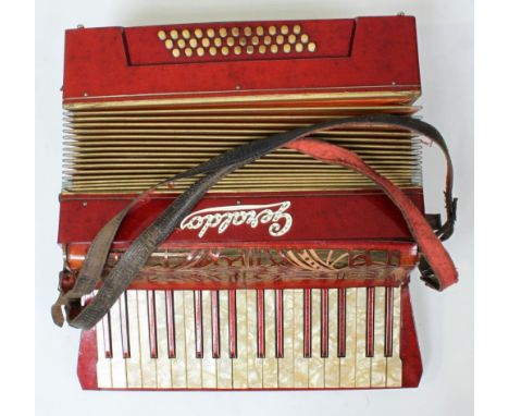 A red accordion by Geraldo with faux mother of pearl keys and leather straps, in black leather case 