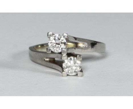 An 18ct white gold two-stone diamond ring, of cross-over design, RBC diamonds each estimated 0.25pts, / 0.50 carats in total,