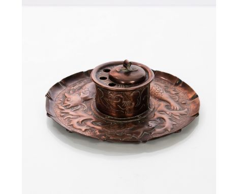 A Newlyn style Arts & Crafts copper ink stand, embossed fish swimming, fitted ceramic liner, the lid with twisted strip finia