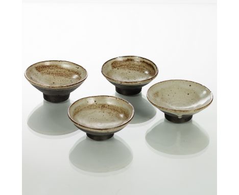 Janet Leach (American 1918-1997), a set of four circular footed dishes, cream glaze to bowl interiors and oxidised unglazed e