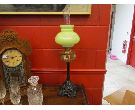 An oil lamp with green glass shade and reservoir