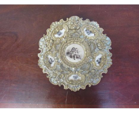 An Edwardian ormolu charger with printed ceramic panels of cherubs, 30cm diameter