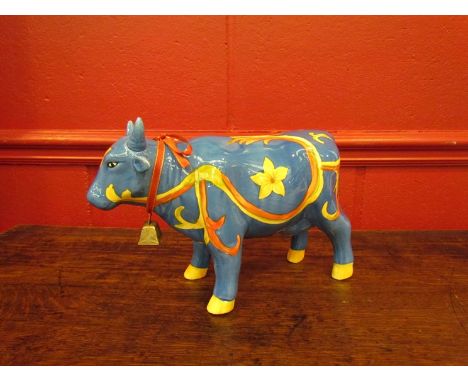 A ceramic money box as a cow printed blue ground, yellow flowers 