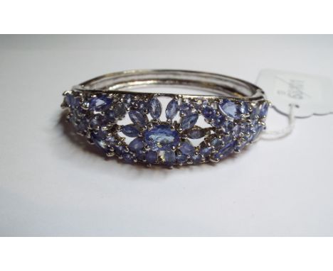 A silver coloured metal and tanzanite bangle
