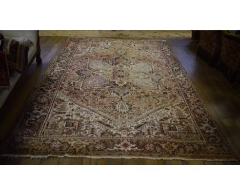 A Heriz carpet, decorated stylised foliate and floral motifs on an ivory ground, within a multi border, 327 x 234 cm 