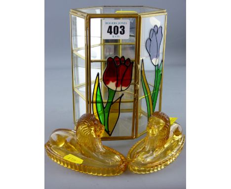 Pair of amber moulded glass reclining lions and a small glass floral decorated miniature trinket cabinet