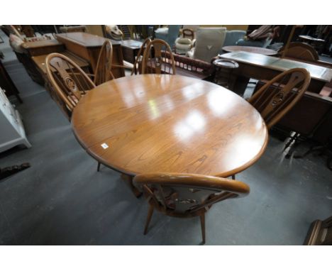 An Ercol elm drop leaf circular dining table and a set of 6 Ercol beech wood swan back dining chairs.(7)