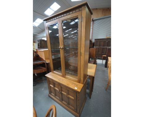 A Medium elm Ercol display cabinet with 2 glazed doors above 2 panelled cupboard doors.