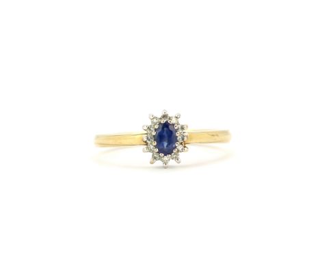 A hallmarked 9ct yellow gold cluster ring set with an oval cut sapphire surrounded by diamonds, (O).