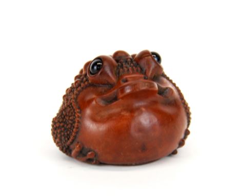 A carved fruitwood Netsuke of Chan the lucky toad with obsidian eyes, Dia. 5cm, H. 4cm.