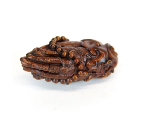 A Chinese carved fruitwood model of praying hands with prayer beads, L. 8cm.