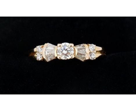 An 18 carat gold ring set brilliant cut diamond flanked by baguette cut diamonds and four smaller stones, 2.8g, size K - L 