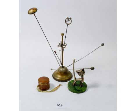 A collection of hat pins and stand, a cat ring stand and a tape measure 