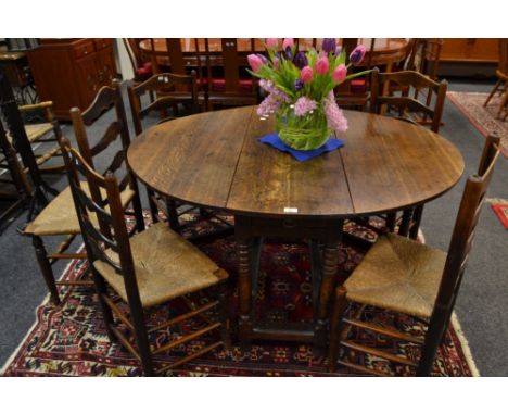 A 19th Century oak drop leaf table, gate leg supports; a set of five rush seat, ladder back dining chairs