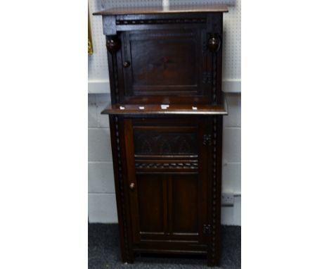 An early 20th Century oak court cupboard of unusually small proportions, acorn finial to frieze, inlaid door, shaped lower si