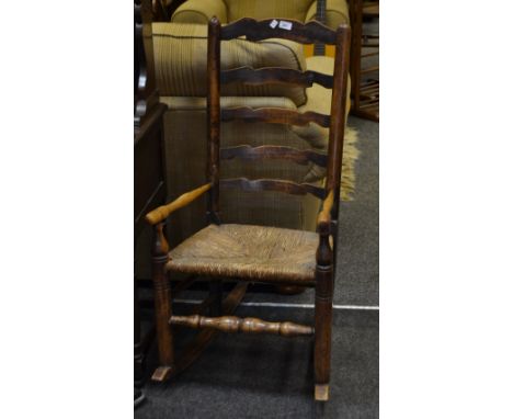 A 19th Century oak ladder back rocking chair, rush seat