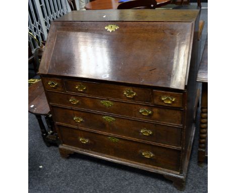 A George III oak bureau, fall front enclosed pigeon holes and drawers, two small drawers flanking short drawer, over three lo