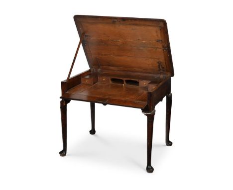 A RARE GEORGE II OAK ARCHITECT'S TABLE  CIRCA 1730 The hinged top and fall front frieze opening to an arrangement of pigeon h
