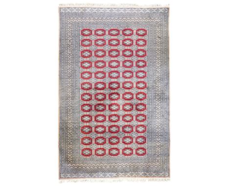Jaldar Bokhara crimson and pale ground carpet, the field decorated with five rows of Gul motifs, within intricate multi-band 