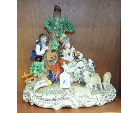 A large Sitzendorf figure group depicting a courting couple sitting beside a tree, she playing a pipe, he holding a tambourin