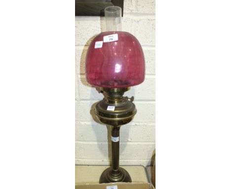 A brassed oil lamp with reeded column and purple glass shade, 72cm high overall.