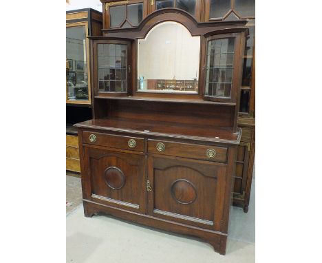An early-20th century mahogany sideboard, the back fitted with a central mirror flanked by bowed leaded-light doors, above tw