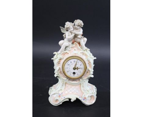 GERMAN PORCELAIN MANTLE CLOCK a late 19thc or early 20thc porcelain mantle clock, mounted with cherubs and with scrolling fee