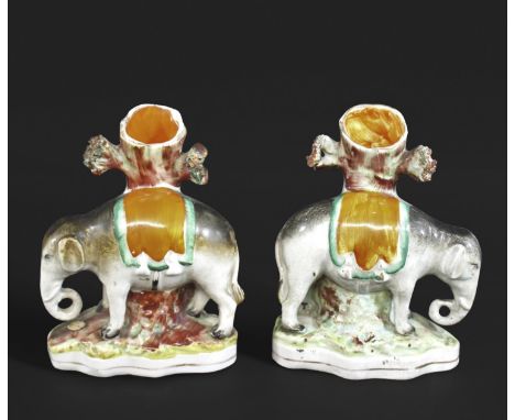 PAIR OF STAFFORDSHIRE ELEPHANT SPILL VASES each modelled as an Elephant leaning against a tree trunk, both with an orange sas