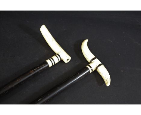 IVORY &amp; EBONY WALKING STICKS two similar walking sticks, the handles formed from ivory tusks with ebony bands, both mount