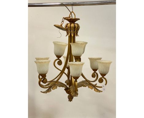A gilt metal chandelier in the baroque taste, with nine scrolling branches and embellished with hammered metal panels formed 