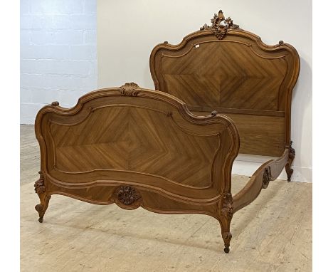 A Louis XV style French walnut double bed frame, late 19th century, the headboard of scrolling form with floral carved surmou