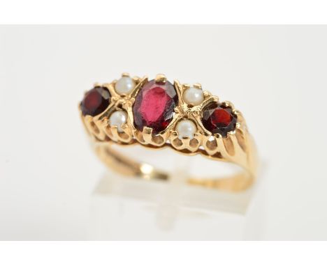 A 9CT GOLD GARNET AND SEED PEARL RING, designed as a central oval garnet flanked by a circular garnet interspaced by two seed