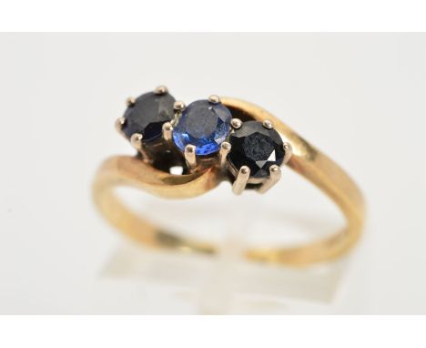 A 9CT GOLD THREE STONE SAPPHIRE RING, designed as three claw set circular sapphires set on an angle to the cross over shoulde