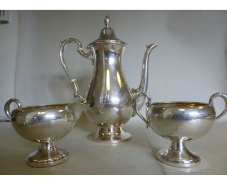 A silver coloured metal coffee pot of ovoid form, having a domed, hinged lid, a C-scrolled handle and a swept spout, on a ped
